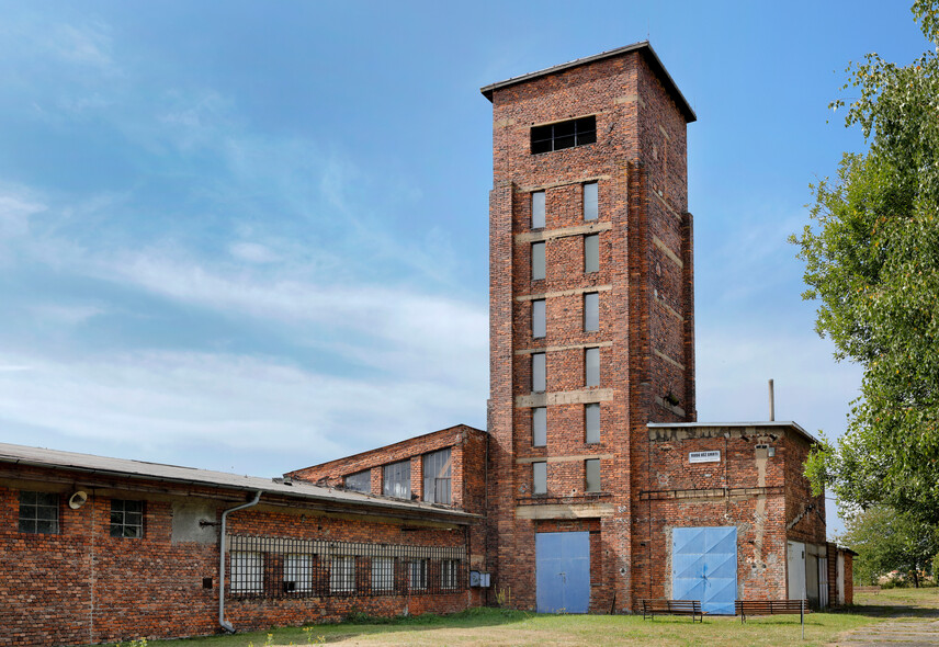 Srpen 2025 pohled na věž ve směru od východu, zamřížovaná okna jsou na kancelářích a laboratořích, kde civilní zaměstnanci zapisovali váhu každého barelu a informace o U rudě
