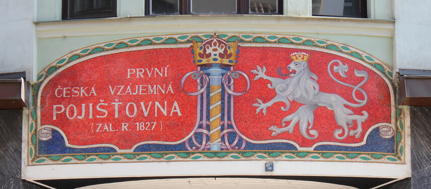 Skleněná mozaika s výrazným nápisovým polem a státním znakem nad hlavním vchodem čp. 76 (2012)