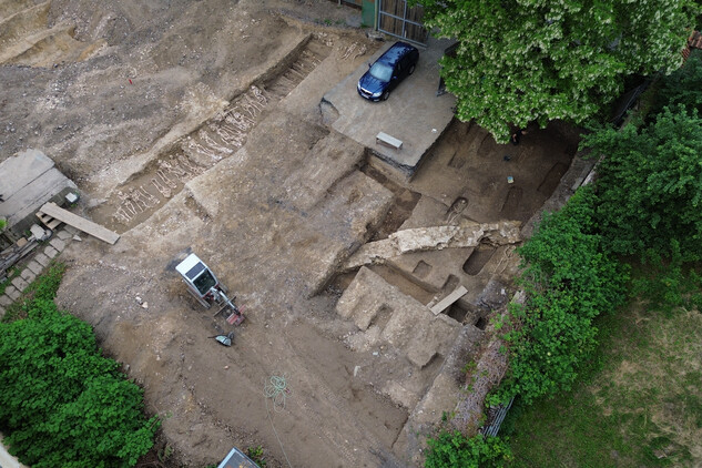 Celkový pohled na severní část zkoumané plochy s liniovým hrobem č. 12 a 17 a z větší části vybranými hroby jedinců v rakvích, které protíná středověká ohradní zeď (foto Egon Ditmar, 28. 5. 2025).